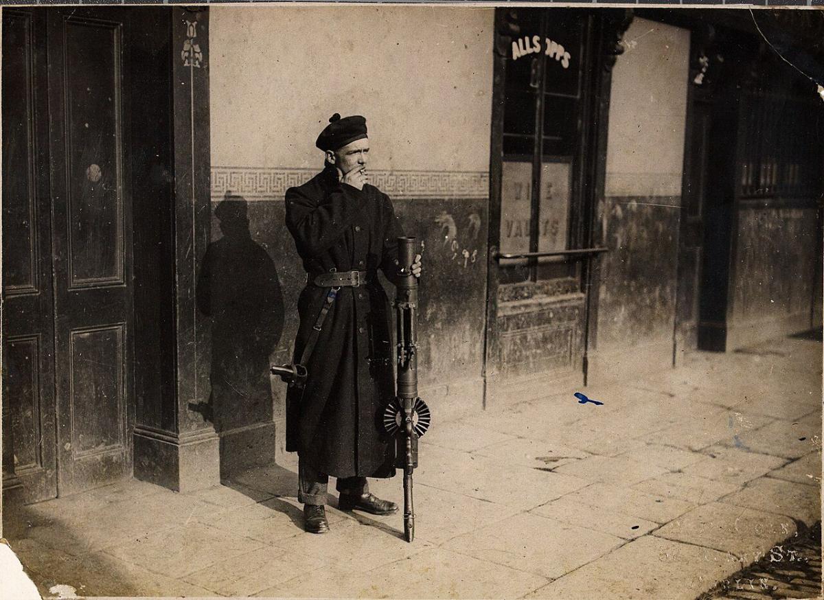 Fotografia antiga de um membro armado das forças auxiliares britânicas de serviço numa rua de Dublin, por volta de 1920